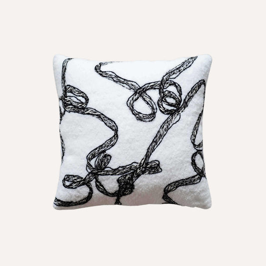Modern wool cushion cover with black and white ribbon patterns.
