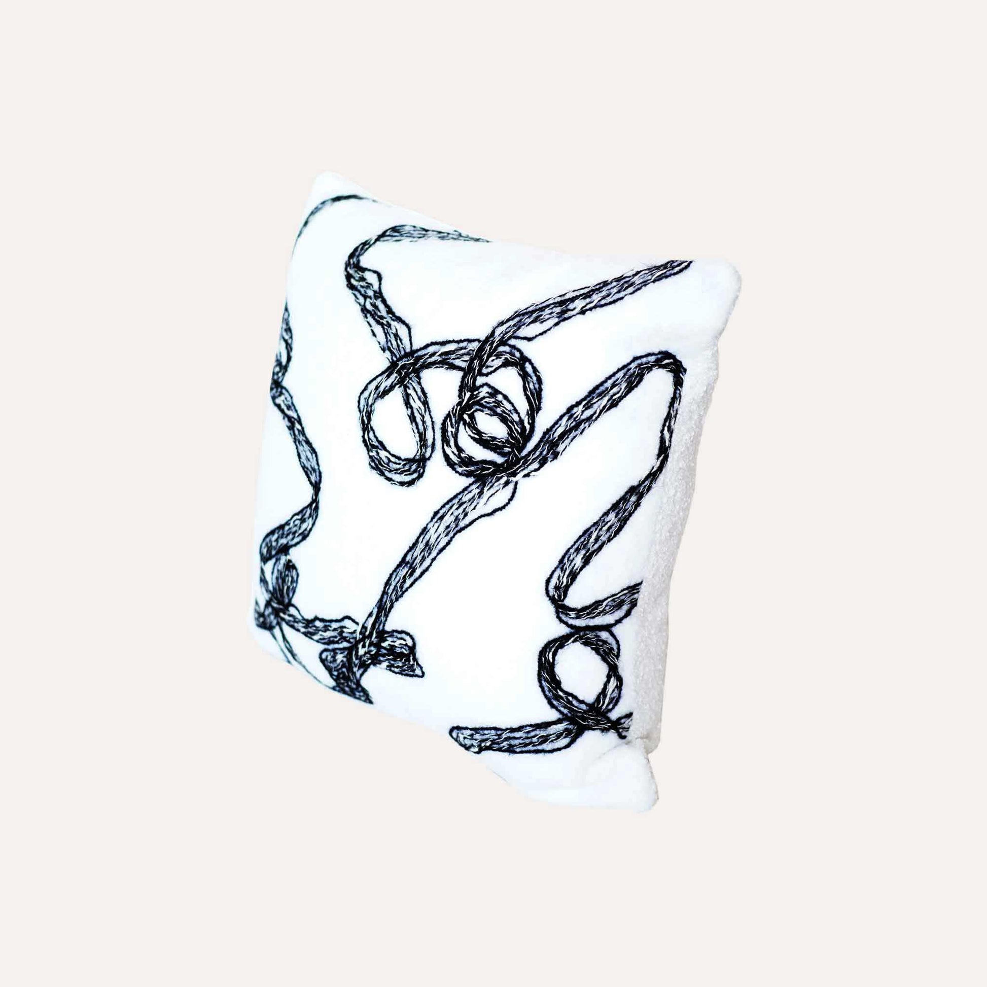 Modern wool cushion cover with black and white ribbon patterns.