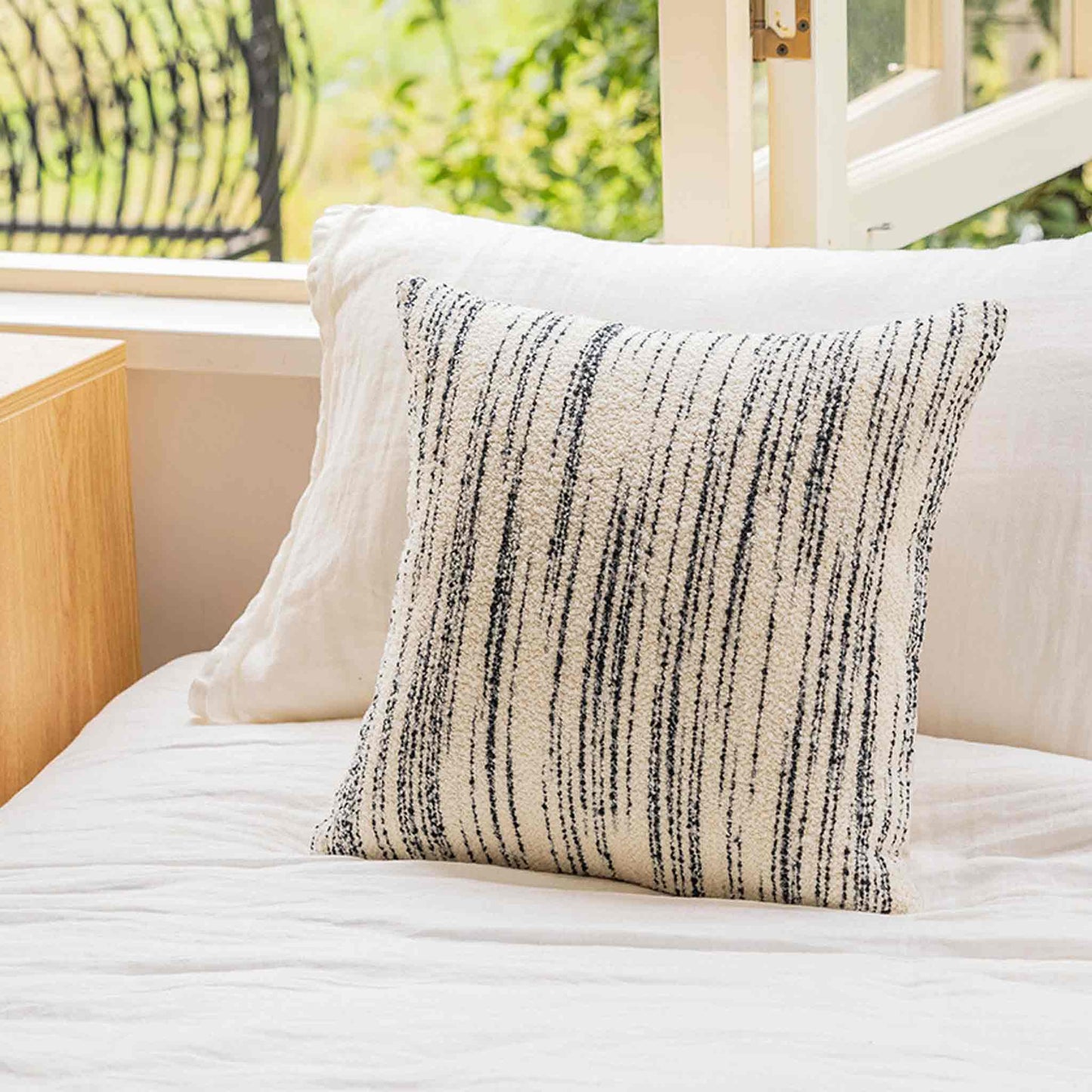 Black and white crayon strokes wool cushion on bed.